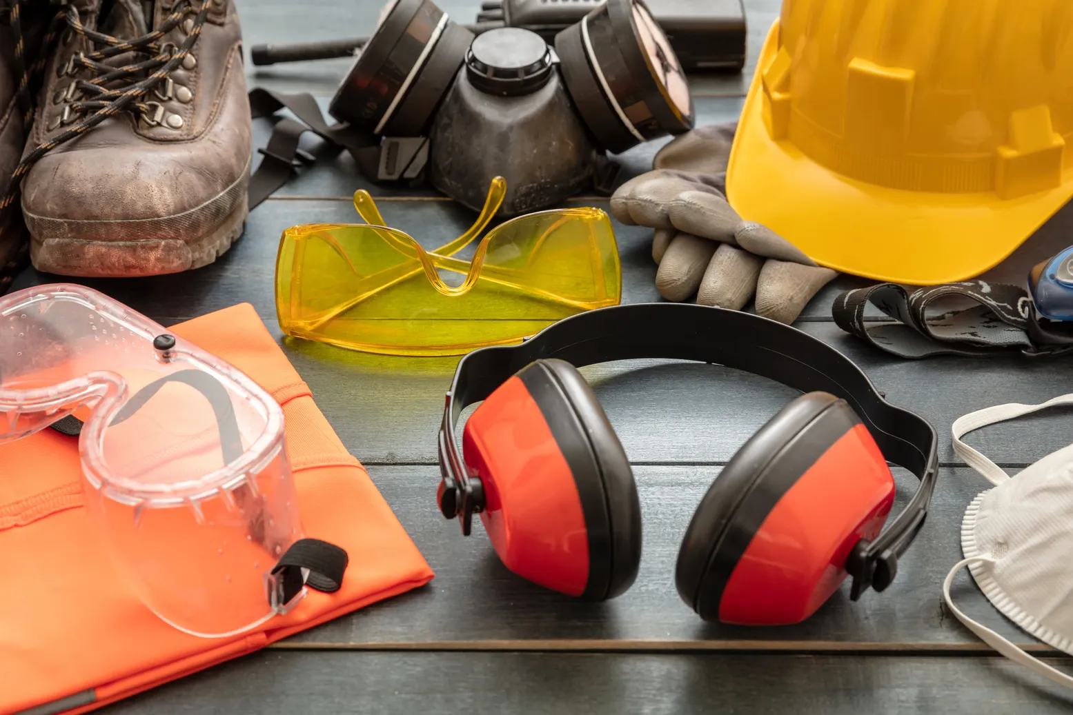 Tipos de accidente de trabajo: Fotografía de un casco, guantes, lentes, mascarilla y zapatos de seguridad industrial. 